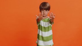 Stop, enough. Preteen child boy kid say no hold hands palms in finish danger gesture, don't want to do it, warning of prohibited access, declining communication, body language on orange background - Powered by Shutterstock - Get 15% off with code: PIKWIZARD15