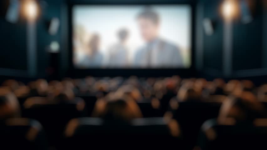 Blurred audience enjoying a love story projected on the big screen in a movie theater
