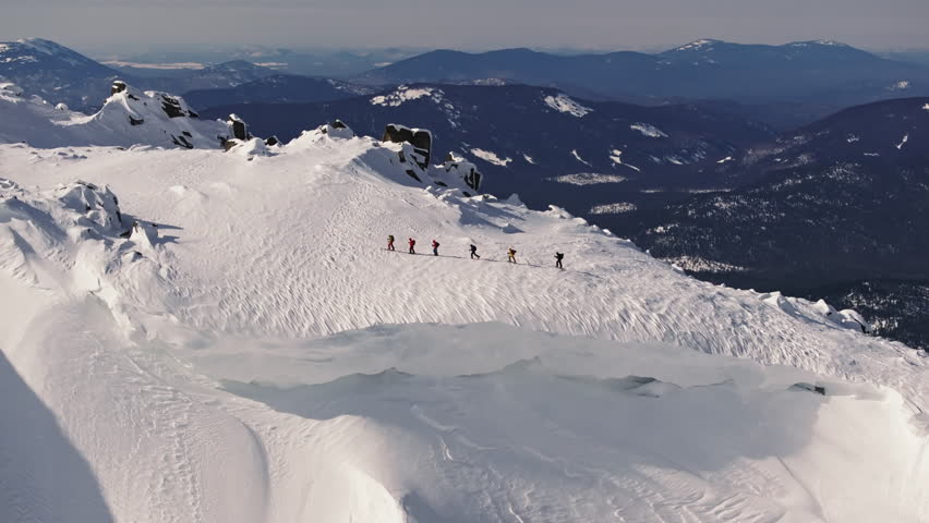 Mountaineers walking on snowy mountain ridge