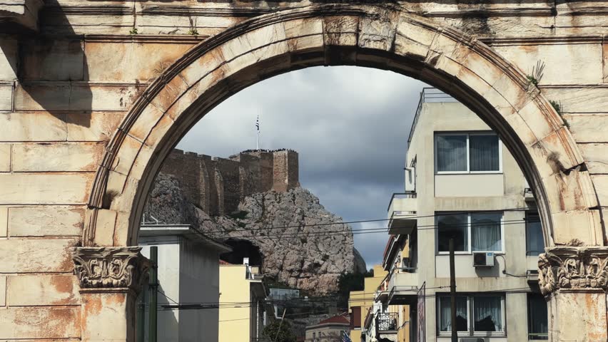 Greek flag on Acropolis seen over Hsdrian gate arch in Athens, Greece
