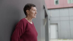 Senior woman leaning against wall, contemplating outdoors - Powered by Shutterstock - Get 15% off with code: PIKWIZARD15