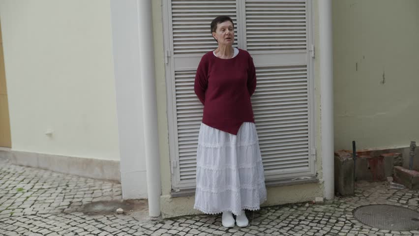 Senior woman leaning against wall, shifting gaze