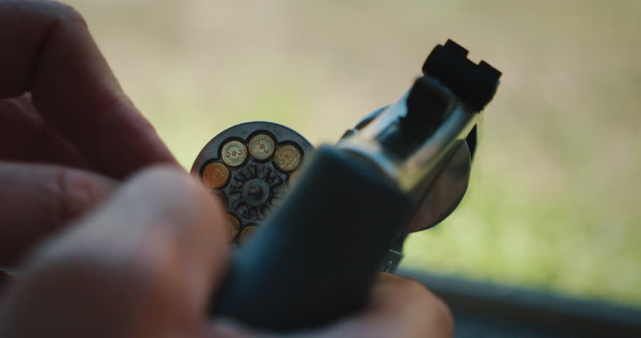 Hands of man loading ammunition into revolver cylinder at shooting range