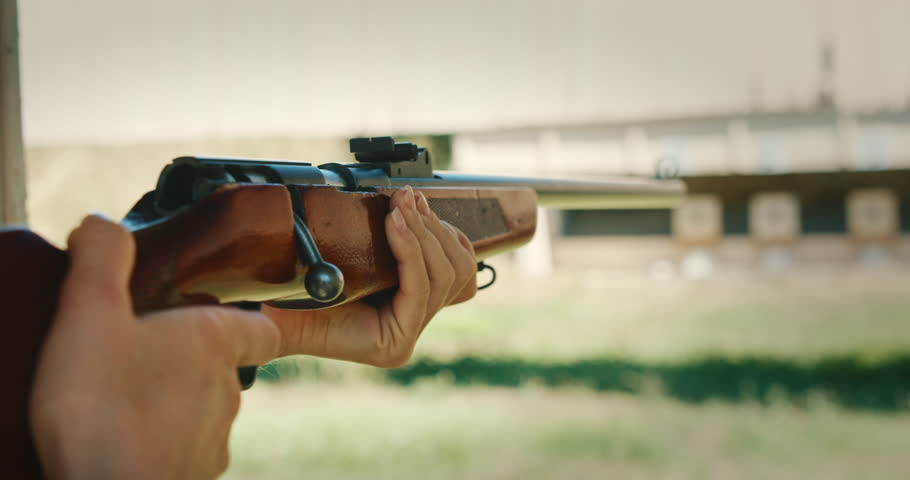 Person aiming bolt-action rifle at shooting range targets