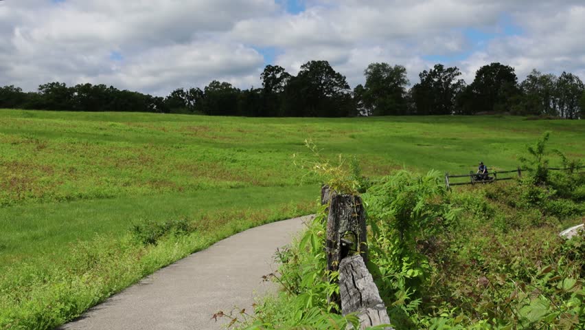 man riding a bicycle on a paved cycleway bike trail (male cyclist biking on asphalt nature path in the countryside rural park) croton point park new york camping camp (touring adventure cycling) usa