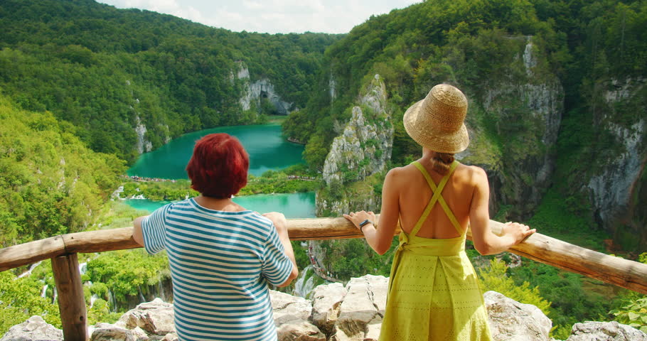 Two women enjoying panoramic view of turquoise lakes and cliffs in Plitvice Lakes National Park Croatia during summer