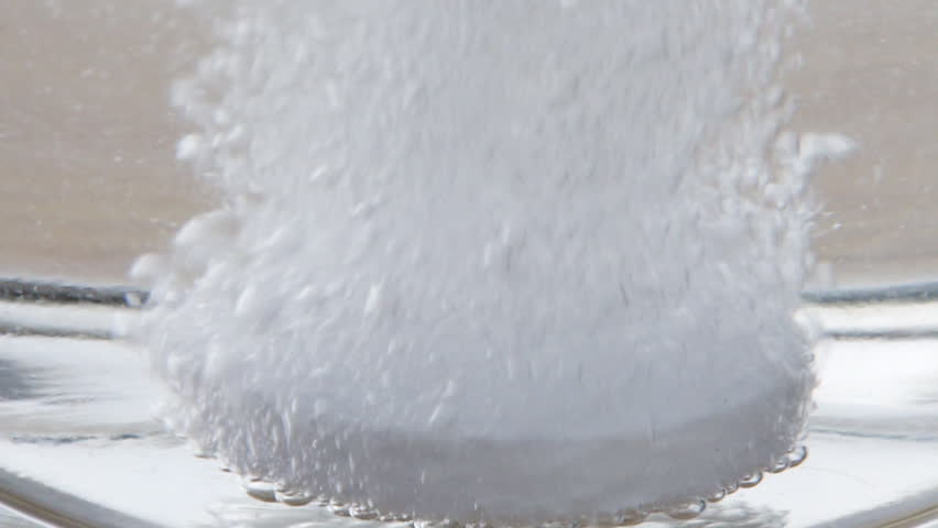 A soluble tablet is dissolving in water. Macro shot. Effervescent pill for producing a liquid solution.