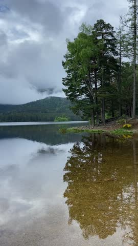 Vertical Video of Misty Lake Reflections in Aviemore, Scottish Highlands with Surrounding Trees and Mountains. Ideal for cinematic B-roll, nature documentaries, travel reels, and  relaxation content