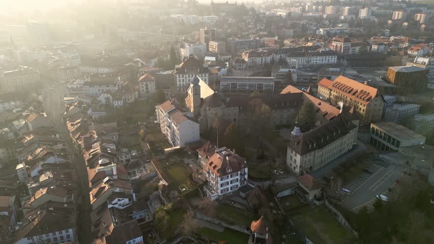Fribourg, Switzerland: Aerial drone footage of the Saint Michel college historic building in Fribourg famous medieval old town at sunset in Switzerland. 