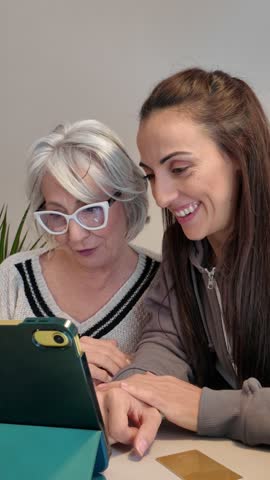 Woman helping elderly mother using smartphone