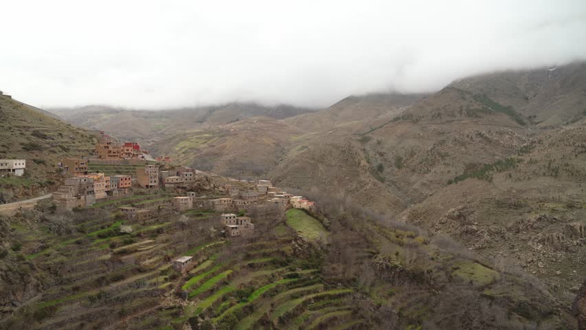 As the sun beams down, snow-covered peaks of Toubkal shine brightly, and the hills around the village come alive with color in Morocco
