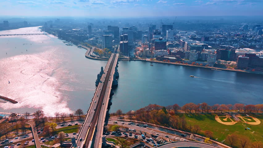 Surface of calm Charles River sparkles beautifully in the sun. Drone flight over the Longfellow Bridge with some cars on. Boston, Massachusetts, USA.