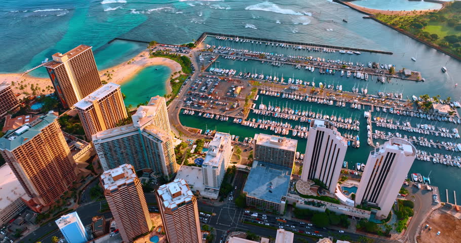 View over the tops of skyscrapers in Waikiki. Numerous yachts are on the anchor at the docks. Honolulu, Hawaii, USA.