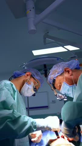Male surgeons cooperate at surgery. Doctor use medical tool devices at operation. Vertical view.