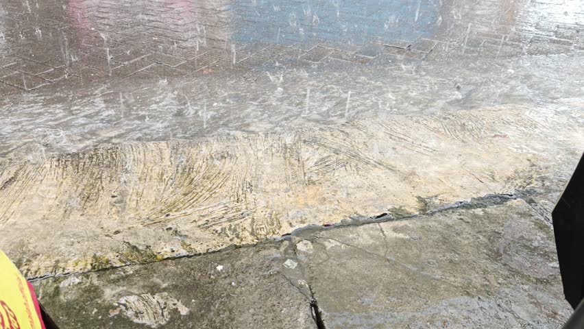 Footage of an Asian man taking shelter from heavy rain during a trip