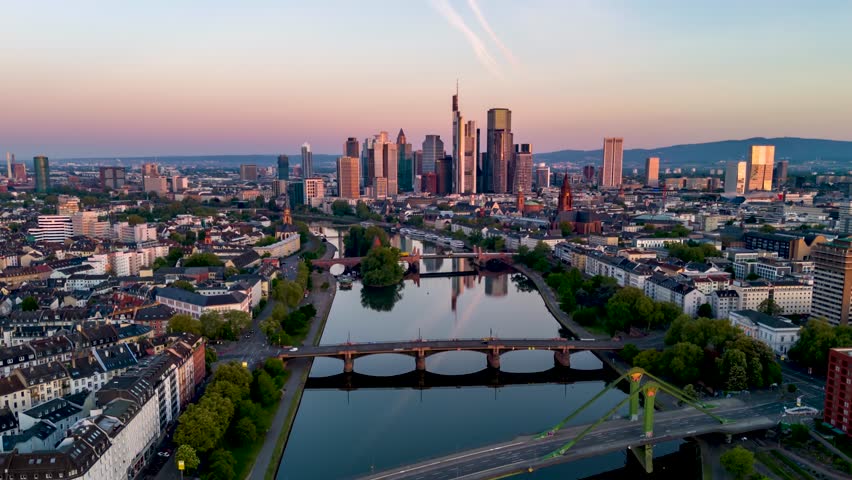 Aerial sunrise hyper time lapse view of the skyline of Frankfurt, Germany, and River Main with golden sunlight