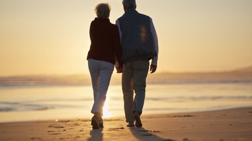 Elderly couple walking on beach at sunset, multiple shots