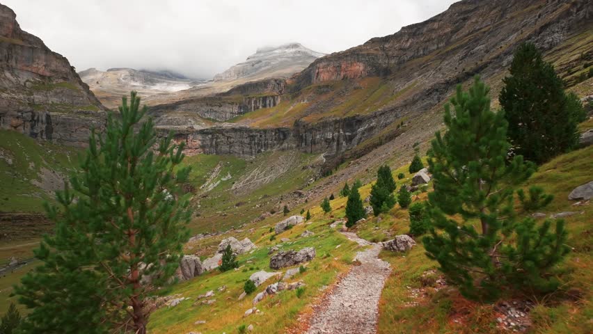POV shot while hiking through Ordesa Valley in Monte Perdido National Park, Spanish Pyrenees. Beautiful mountain landscape with the Soaso Glacier Cirque and Cascada de la Cola de Caballo waterfall