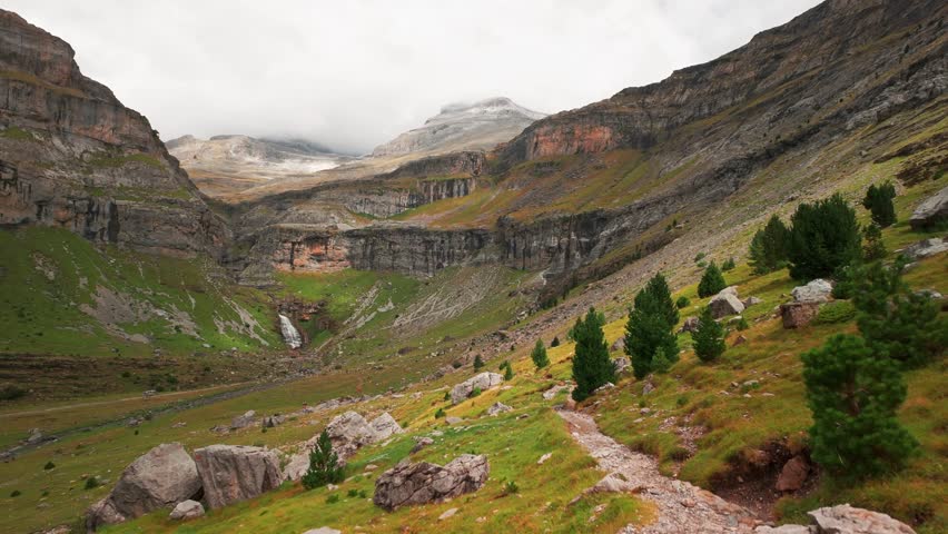 POV shot while hiking through Ordesa Valley in Monte Perdido National Park, Spanish Pyrenees. Beautiful mountain landscape with the Soaso Glacier Cirque and Cascada de la Cola de Caballo waterfall
