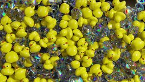 Yellow rubber ducks and iridescent soap bubbles falling, gently accumulating on dark surface, creating whimsical abstract visual composition with playful movement and dynamic. 3D Illustration - Powered by Shutterstock - Get 15% off with code: PIKWIZARD15