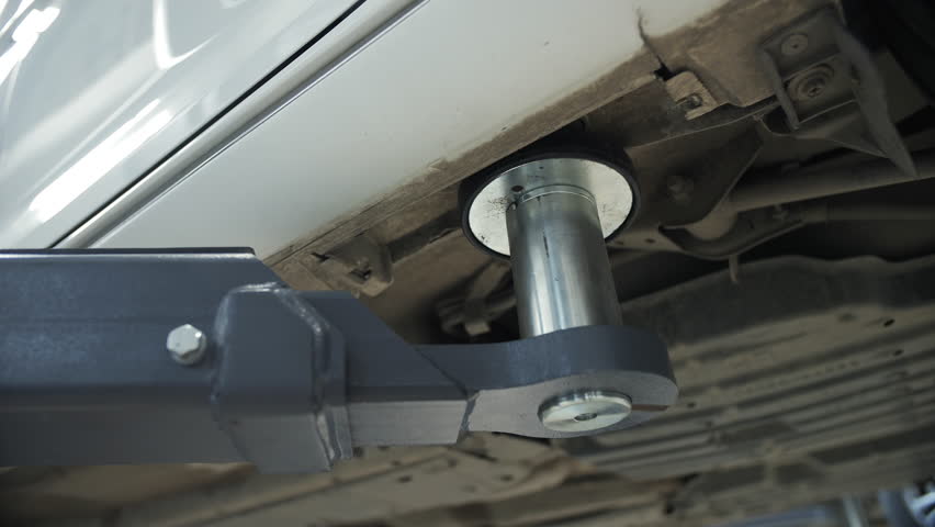 Car lifted by hydraulic support arm in auto service shop