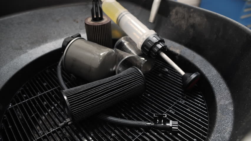Used automotive oil filters and tools in service station tray