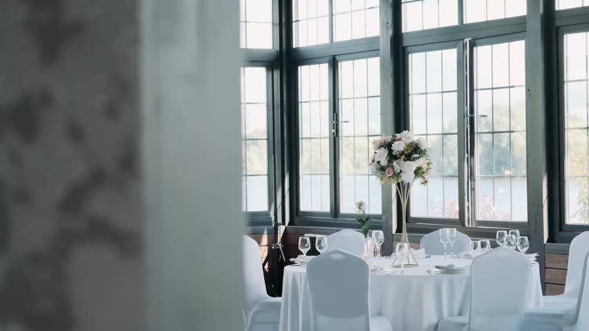 tables in the restaurant are covered with tablecloths with glasses and plates.
