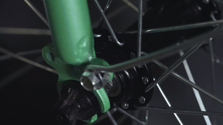 Bike wheel axle assembly with turquoise frame macro view.
Video of bicycle wheel hub mechanism showing the central axle, black metal components, and spokes connection with turquoise blue bike frame in