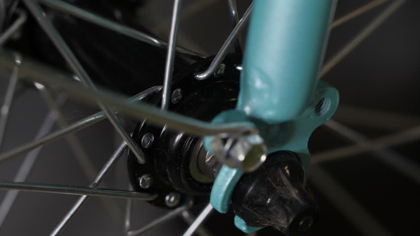 Bicycle wheel hub and spokes mechanism closeup detail shot.
Video of bicycle wheel hub mechanism showing the central axle, black metal components, and spokes connection with turquoise blue bike frame 