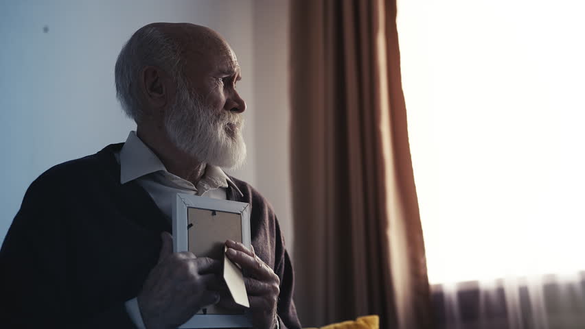 Unhappy pensioner crying while looking at photo of child, emotional family loss