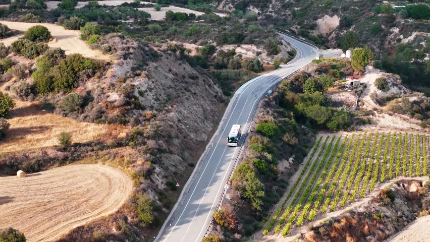Aerial drone view winding mountain road between autumn trees.