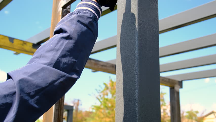 Man painting metal poles. Selective focus.