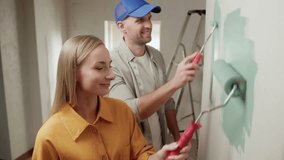 Happy couple renovating their new home, painting walls with light green paint using a roller, smiling and enjoying the process of transforming their space together - Powered by Shutterstock - Get 15% off with code: PIKWIZARD15