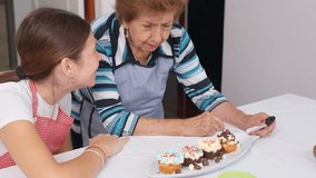 Grandmother and granddaughter sharing a heartwarming moment while decorating cupcakes in the kitchen - Powered by Shutterstock - Get 15% off with code: PIKWIZARD15