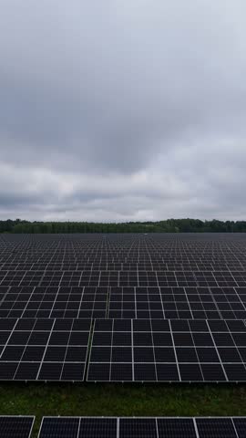 Large solar panel array under cloudy sky in green rural landscape renewable energy concept