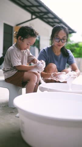 Cute toddler helping his mom wash socks with soap suds during laundry time. A sweet and candid parenting moment showing family bonding, early responsibility, and everyday love.