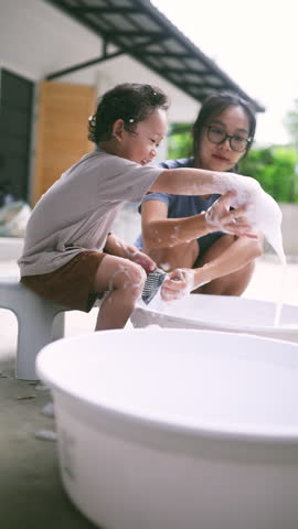 Cute toddler helping his mom wash socks with soap suds during laundry time. A sweet and candid parenting moment showing family bonding, early responsibility, and everyday love.