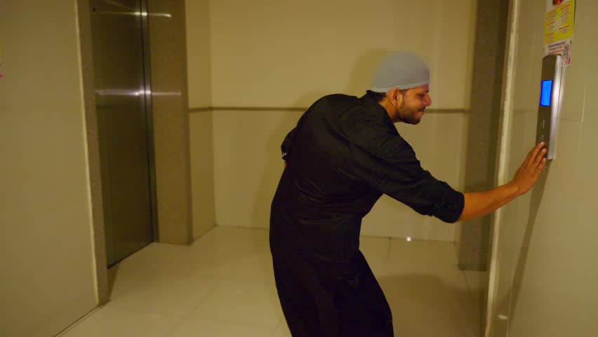 Agitated man repeatedly hits lift panel in panic, Upset guy taps elevator button several times, Distressed male hastens push on floor switch, Grieved muslim stand by corridor with rising tension, Sad