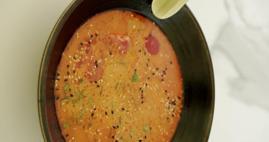 Delicious Vegetable Soup Rotating on white background. cream tomato and Vegetable soup with ingredients and lime in black plate on white background. Vertical video for stories.