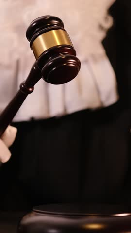 Gavel striking in courtroom with law books, symbolizing justice and legal authority. Vertical video