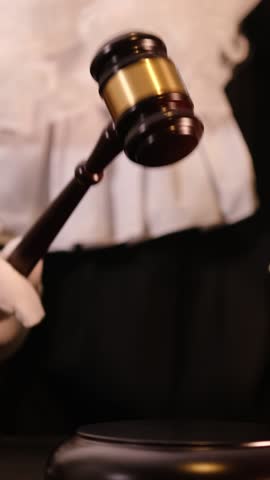 Gavel striking in courtroom with law books, symbolizing justice and legal authority. Vertical video