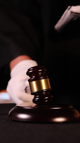 Judge preparing to make an important ruling with gavel and legal books in courtroom setting. Vertical video
