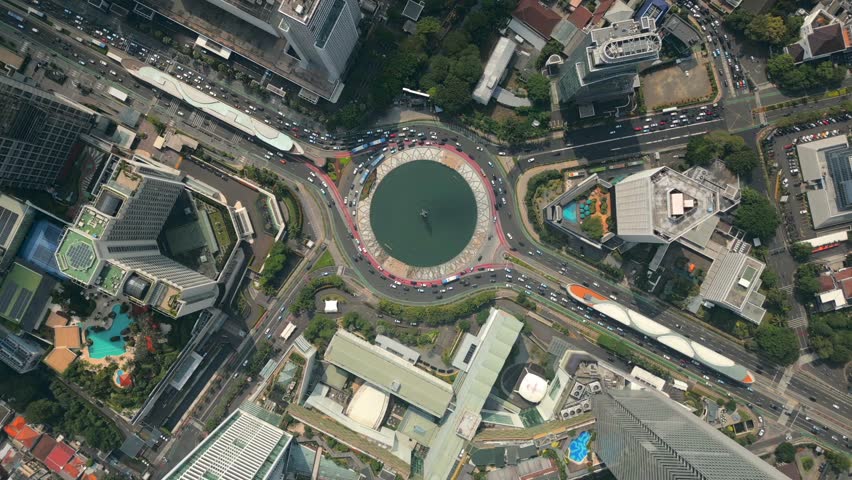 Aerial top-down view of busy traffic at roundabout with modern buildings in central Jakarta, Indonesia. Perfect for city, architecture, and tourism themes.
