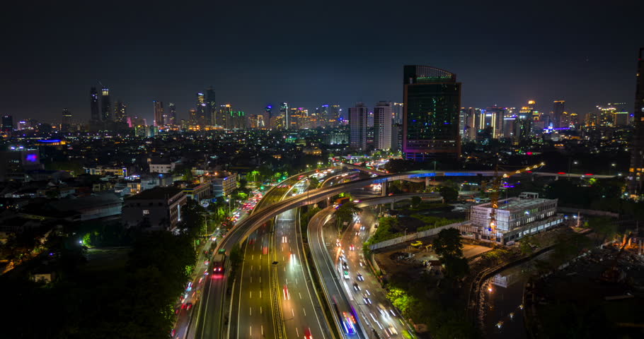 Aerial hyperlapse of Jakarta city with busy traffic on highway and glowing skyline at night, Indonesia. Perfect for urban, travel, and infrastructure themes.