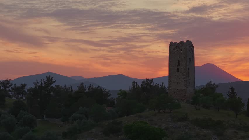 Drone Orbit Around Ancient Stone Observation Tower at Sunset with Orange Sky