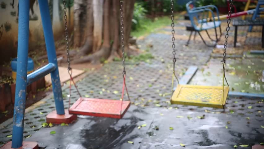 The swing in the park was swinging in the afternoon after the rain stopped