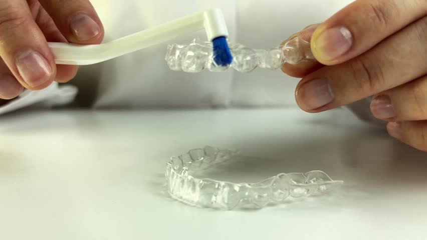 Cleaning dental aligners with a brush. 