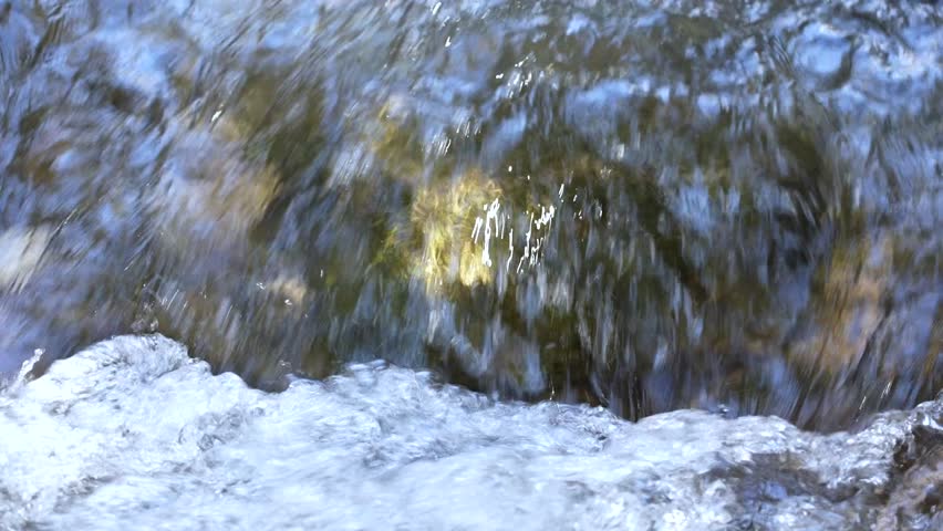 Close-up of fresh water falling over rocks, captured in motion. Pure and dynamic stream with splashes and reflections
