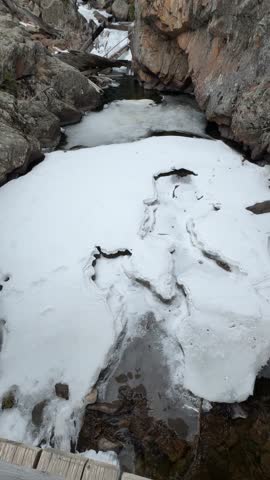 View down a canyon with a frozen stream and waterfall in Rocky Mountain National park