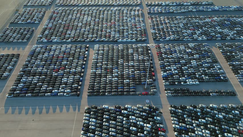 New Cars on Large Full Parking Lot in Port Ready for Distribution. Harbor Vehicle Storage for Export and Import. Automotive Industry. Aerial View. Moving Forward